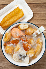 top view seafood porridge with crabs and shrimps and white shells and deep-fried dough sticks