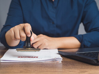 Businesswoman stamped approved on a document while sitting in the office