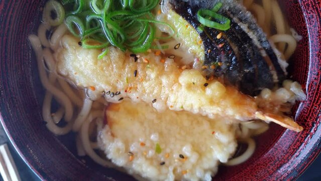 Top view slowmotion video udon jpanese noodle hot soup with tempura shrimp eggplant sweet jam local healthy food
