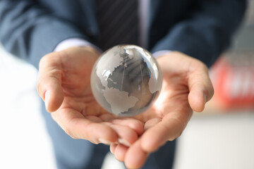 Lucky businessman holds glass globe with continents in hands