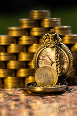 Pyramid of golden coins, 100 Kazakh tenge coin and vintage pocket watch