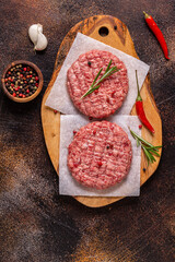 Fresh raw minced homemade grill beef burgers on wooden chopping board