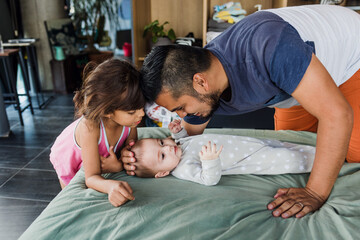 young latin single father with baby son and daughter on bed at home in Mexico Latin America,...