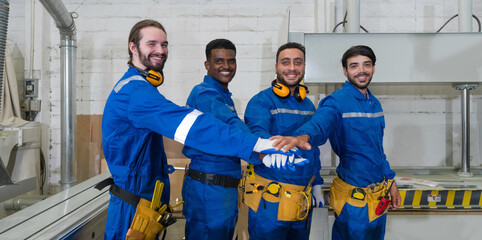 Group of technician in blue mechanic jumpsuit, ear muff and yellow tool belts join hand together in...