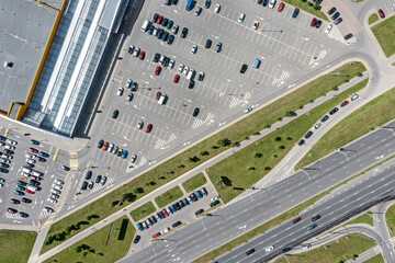 shopping mall parking lot with many parked cars. top view aerial photo in sunny summer day.