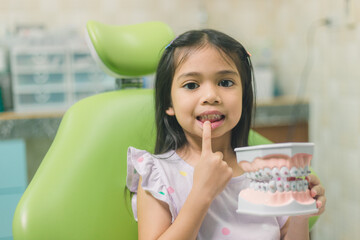 Asian girl in dental chair, with tooth brush. Medicine, dentistry and healthcare concept