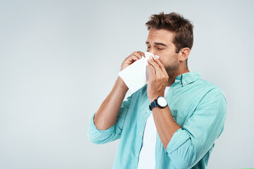 Allergy, sick and man blowing nose in tissue with flu, illness and virus on studio background. Health mockup, wellness and face of male person with handkerchief for hayfever sinus, cold and sneeze