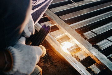 Industry worker wearing white glove and welding iron at work outdoor. Close-up hand tool for welding steel. Concept industrial using welding machine for construction.