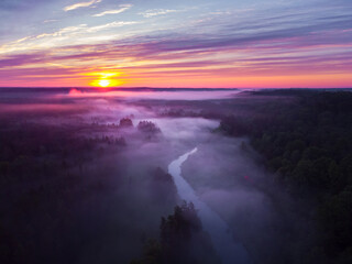 Fototapeta premium Drone's Eye View: Serene Sunrise Over Misty River and Woodland Landscape in Northern Europe