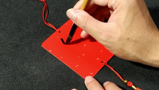 Writing Chinese Calligraphy characters,translation: "Health" on Red Sprinkled Gold Card.