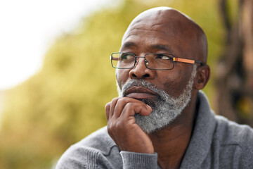 Senior man, face and thinking outdoor in nature to remember memory, idea or vision. Headshot of an elderly African male person think or planning future, life insurance or retirement at a park