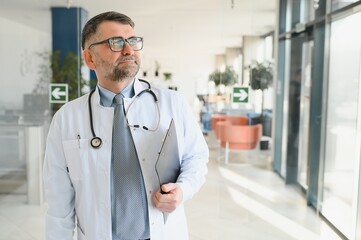 Portrait of serious senior doctor in eyeglasses and in white coat.