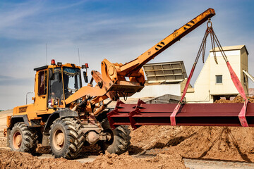 Heavy front loader for transportation of bulky goods. Moving bulky goods on the construction site. Heavy construction equipment for transporting materials.