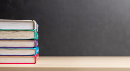 Stack of books on desk with chalkboard