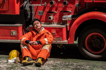 The firefighter tired from rescuing a victim from a fire situation sits back against the fire truck...