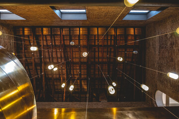 Detail of beautiful copper spiral staircase with long lamps with warm light in the wood ceiling