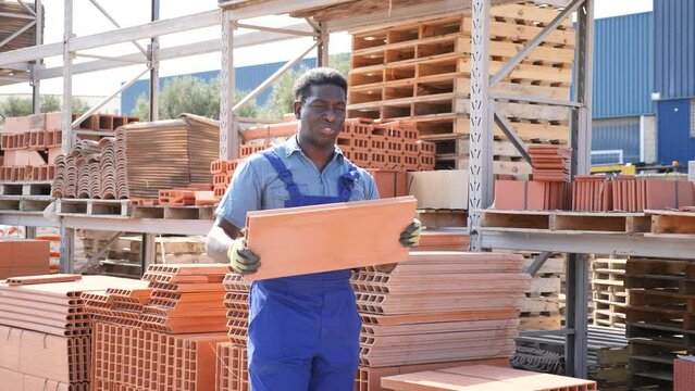 African american worker stacking bricks in warehouse of building materials. High quality 4k footage