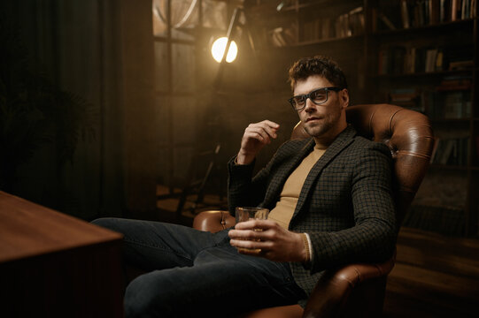 Portrait of young adult elegant gentleman drinking alcohol rest in armchair