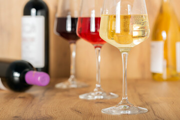 Tasting experience in the rustic cellar and wine bar: glass of red, white and rosé wine and collection of fine wines in the background