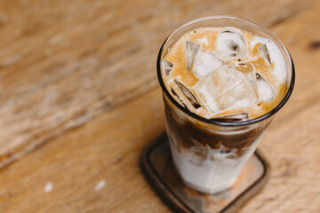 iced coffee, cold milk latte with ice on wood table background copy space for text