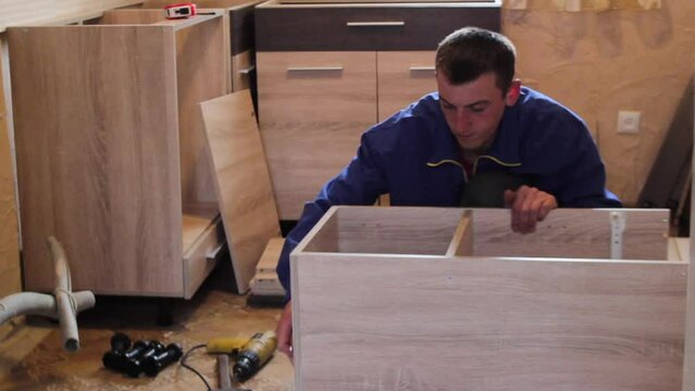 assembling kitchen furniture,a young furniture assembler is assembling the kitchen
