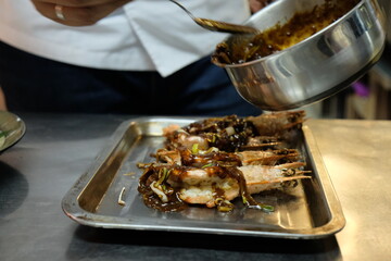 Cook pours onion sauce on a shrimp dish