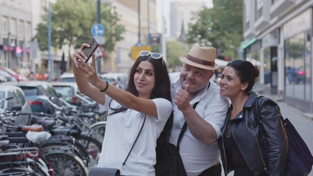 Three tourists making a selfie using a cellphone while visiting a city in summer