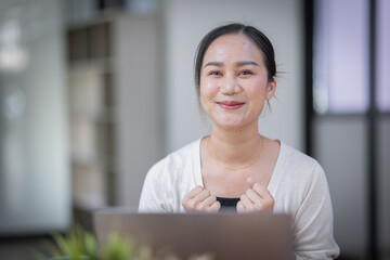 Happy excited successful business asian woman triumphing in office, Portrait of a cheerful Asian businesswoman sitting at the table in office,
