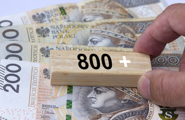 Hand holding wooden block with inscription 800 plus. 800 plus is evaluation of the 500 plus program in Poland, state program in the field of social policy, 