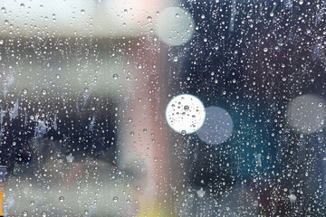 blurred and bokeh rain drops on glass window surface, rainy day background