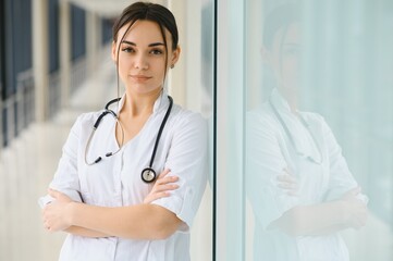 Portrait of young female doctor standing in hospital corridor. Caucasian woman working in nursing home.