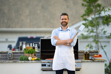 chef man at barbecue and grill hold utensil, copy space. chef man at barbecue and grill outdoor.