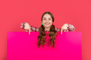 happy child behind blank pink paper with copy space for advertisement. point finger