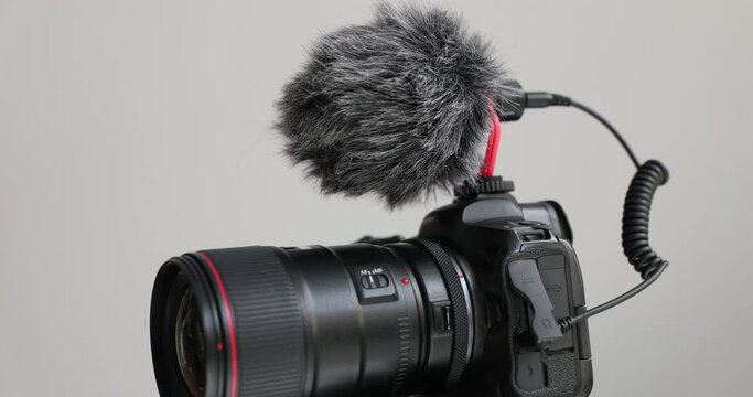 Professional camera with microphone with fur cover. Equipment for making photos and videos in light studio. Optical instrument for high-quality shooting