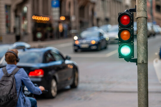 view of city traffic with traffic lights, in the foreground a semaphore with a green light, closeup