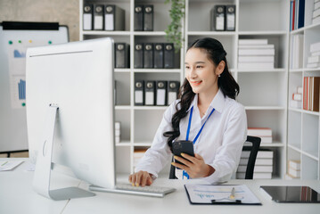  Beautiful Asian business woman typing laptop and tablet Placed at the table at home office