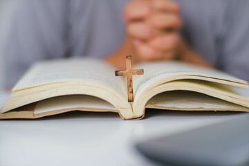 Close-up of a woman reading an open bible, praying and holding hands on her bible. Spiritual or bible study concept.