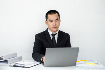 Smart businessman’s sitting in the office room and using computer to plan about marketing investment for his business.