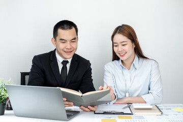 Obraz premium Two business people sitting at workplace and discussing about earnings on a graph to plan investments.