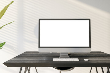 Front view of a home workplace with black desk with blank screen modern computer on light wall background in sunny interior, mockup. Home office and freelane work concept. 3D Rendering
