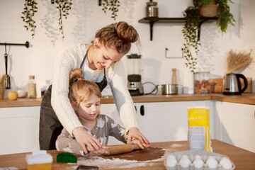  Mother and daughter rolling out cookie dough together in a bright, cozy kitchen