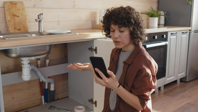 Caucasian woman having problem with water leakage in kitchen getting consultation on video call