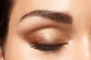 Beautiful close-up of closed female eye with fashion smoky make-up, perfectly shaped eyebrow, brown...