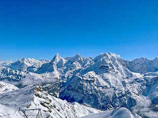 Scenic winter landscape in the Swiss Alps with famous peaks Eiger, Monk and Virgin seen from cabin of Schilthorn cable car cabin on a sunny winter day. Photo taken March 19th, 2021, Switzerland.
