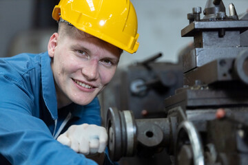 Close up caucasian man engineering workers wear yellow hard hat working machine lathe metal in...