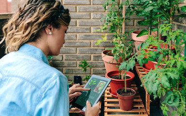 Young woman scanning plants by artificial intelligence in gardening app for tips on caring her...