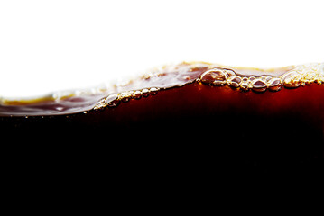 Close-up of a cola drink with foam on a white background.