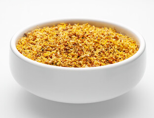 Close-up of dried osmanthus flowers in a white bowl on a white background, isolated, side view. Herbal medicine. Therapeutic tea.