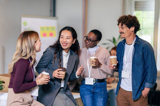 Happy diverse colleagues have fun at lunch break in office, smiling multiracial employees laugh and talk  drinking coffee