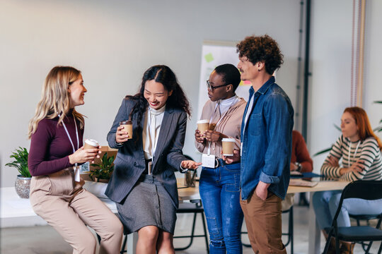 Happy diverse colleagues have fun at lunch break in office, smiling multiracial employees laugh and talk  drinking coffee - Powered by Adobe